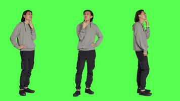 Asian adult questioning perspective standing in greenscreen studio, thinking about answer and pondering solution. Person being in a dilemma trying to focus, pensive unsure adult thinker. video