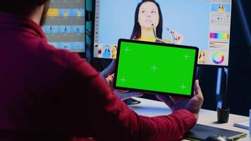 Foto Editor Verwendet Grün Bildschirm Tablette zu Uhr online Podcast während suchen beim Bilder genommen mit Fachmann Kamera. Freiberufler im Zuhause Studio Surfen Bilder und suchen beim Videos auf Attrappe, Lehrmodell, Simulation Gerät