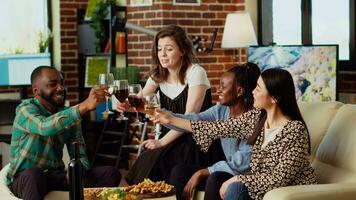 multirracial grupo de personas celebrando su amistad juntos, tostado vino y champán lentes a hogar fiesta. alegre amigos teniendo reunión reunión, disfrutando alcohólico bebidas video