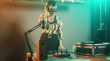 fêmea artista usando mistura gira-discos e botões para jogar remixado canções às festa, tendo Diversão com audio dj borda para techno Boate. jogando graves sons com eletrônicos. portátil tomada. video