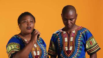 brincalhão casado casal gravação música em Smartphone, desfrutando karaokê sessão com moderno músicas. africano americano homem e mulher cantores usando gravador aplicativo em Móvel dispositivo dentro estúdio. video