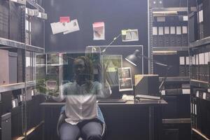 Woman detective looking at evidence in hologram, examining augmented reality image to solve crime in police archive room. Private investigator working with artificial intelligence. photo