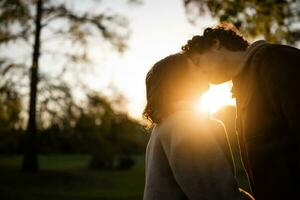 retrato de contento amoroso Pareja en parque en puesta de sol. Pareja en silueta besando foto