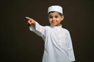 AI generated A young boy in traditional Muslim clothing, smiling and pointing with his finger. photo