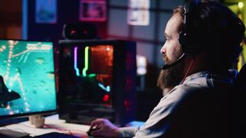 Happy man using headphones to play spaceship flying singleplayer game with overlay HUD showing health, fuel, ammo bars and minimap. Smiling gamer immersed in gaming experience, navigating universe video