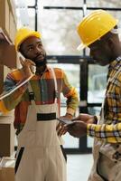 Warehouse manager listening to supervisor explaining inventory management on landline phone. All black storehouse workers team discussing products stock supply with distribution operator on telephone photo