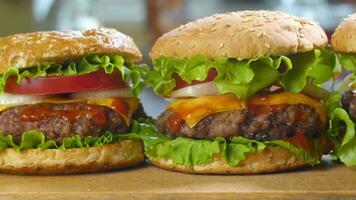 Fresh appetizing Beef Burgers on the kitchen table. Delicious burger with fresh iceberg cabbage, onions, tomatoes and grilled steak. Fast food, track camera movement, 4k video