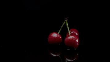 Cerise lent mouvement fermer chute dans l'eau avec éclaboussure gouttelettes sur noir Contexte macro coup cuisine vidéo video