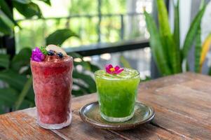 Red and green fruit smoothies in glasses on wooden table photo