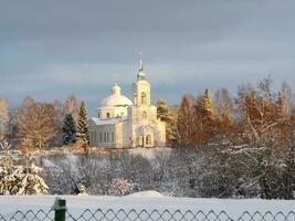 a church in the snow with trees and a fence photo