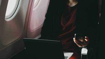 jeune femme asiatique utilisant un ordinateur portable assis près des fenêtres en première classe en avion pendant le vol, les voyages et le concept d'entreprise video