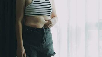 mujer gorda, barriga gorda, gordita, mujer obesa mano sosteniendo grasa abdominal excesiva con cinta métrica, concepto de estilo de vida de dieta de mujer video