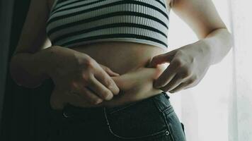 mulher gorda, barriga gorda, gordinha, mão de mulher obesa segurando gordura excessiva da barriga com fita métrica, conceito de estilo de vida de dieta de mulher video