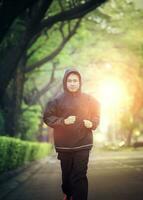 deporte sano hombre vistiendo capucha chaqueta corriendo en verde parque foto