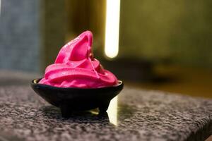 a delicious pink soft serve ice cream in black bowl photo