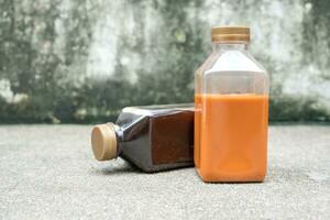 Black coffee and Thai milk tea in plastic bottle on a cement background photo