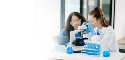 Two scientist or medical technician working, having a medical discuss meeting with an Asian senior female scientist supervisor in the laboratory with online reading, test sample photo