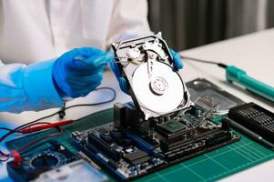 Hard disk drive on the technician's desk and a computer motherboard as a component. the concept of data, hardware, and information technology. photo