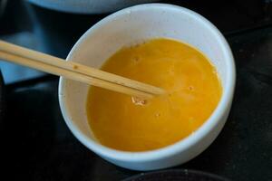 Hand whisk eggs in bowl. Cooking omelette for breakfast. photo