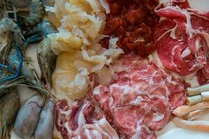 An assortment of ingredients for shabu shabu, fresh sliced meat and sea food photo