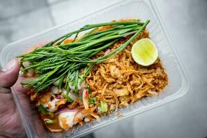 Hand holding oysters in spicy salad in box. photo