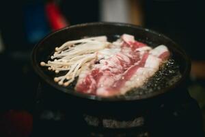 Cooking raw beef and golden needle mushroom on grilled meat on hot pan photo