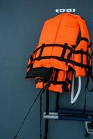 Orange life jackets hanged on wall by swimming pool. photo