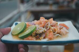 Fresco salmón crudo picante Mariscos ensalada en hombre mano foto