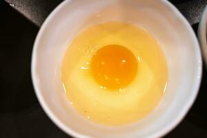 Fresh raw egg in a white bowl photo