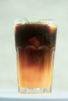 vaso de con hielo americano negro café mezclado con naranja jugo foto