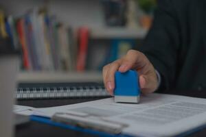 Man stamping approval of work finance banking or investment marketing documents on desk. photo