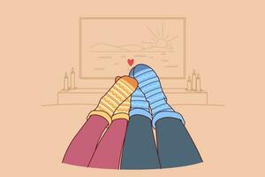 Feet of loving couple in autumn warm socks lying on sofa and watching TV in romantic home atmosphere vector