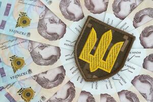 Ukrainian military symbol and hryvnia bills. Payments to soldiers of the Ukrainian army, salaries to the military photo