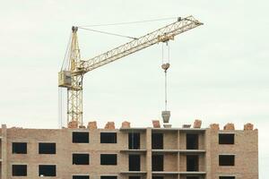 View of a large construction site with buildings under construction and multi-storey residential homes. Tower cranes in action on blue sky background. Housing renovation concept photo