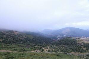 Morning view from the Dragobrat mountain peaks in Carpathian mountains, Ukraine. Cloudy and foggy landscape around Drahobrat Peaks photo