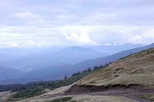 Morning view from the Dragobrat mountain peaks in Carpathian mountains, Ukraine. Cloudy and foggy landscape around Drahobrat Peaks photo