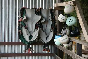 Climbing equipment - colorful helmets and safety vests hanging on a board in a rope park photo