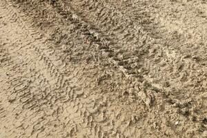 Wheel track on mud. Traces of a tractor or heavy off-road car on brown mud in wet meadow photo