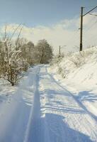 la carretera que se encuentra paralela a la vía férrea está cubierta de nieve en un día soleado después de una fuerte nevada foto