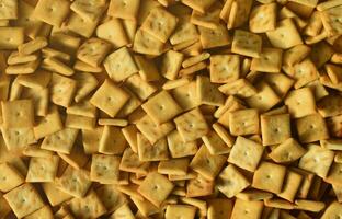 Background texture of small edible squares baked from dough and sprinkled with salt. A lot of salt cracker photo