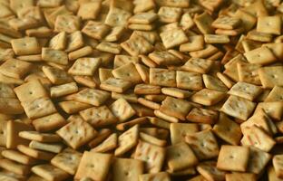 Background texture of small edible squares baked from dough and sprinkled with salt. A lot of salt cracker photo
