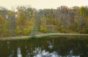 Beautiful Nature Autumn landscape with lake. Scenery view on autumn city park with golden yellow foliage in cloudy day photo