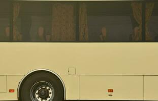 Photo of the hull of a large and long yellow bus with free space for advertising. Close-up side view of a passenger vehicle for transportation and tourism