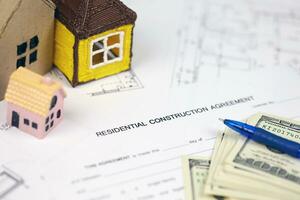 Residential construction agreement ready to sign with small toy houses and pen. Construction contract photo