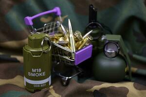 Rifle cartridges in small shopping cart. Big caliber ammo cartridges and hand grenades with a small shopping basket photo