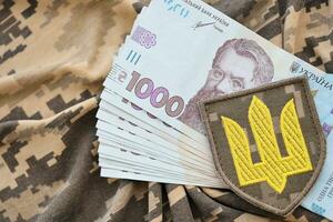 Ukrainian army symbol and bunch of hryvnia bills on military uniform. Payments to soldiers of the Ukrainian army, salaries to the military photo