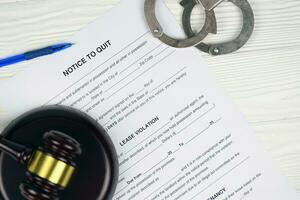 Notice to quit or eviction notice blank document paper ready to fill with handcuffs and judge mallet on table photo