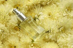 Women fragrance perfume bottle with flowers background close up. Unnamed blank sprayer bottle of perfume photo