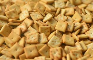 textura de fondo de pequeños cuadrados comestibles horneados de masa y espolvoreados con sal. mucha galleta salada foto