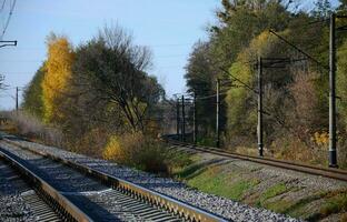 paisaje industrial de otoño. ferrocarril retrocediendo en la distancia entre árboles de otoño verdes y amarillos foto